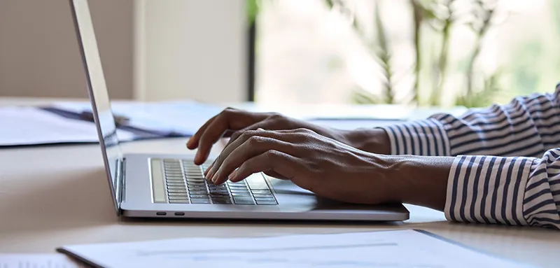 Young black female hands typing on pc keyboard. African business woman user using laptop computer working online.