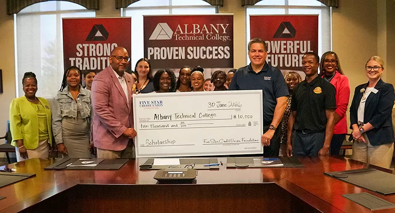 Photo of Dr. Emmett Griswold (ATC President) & Mike Bridges (Vice President of Membership Acquisition and Community Development) Holding a check with ATC students in the background.