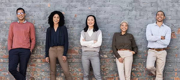 Business team standing together, leaning on a brick wall.