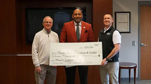 Edward C. Newsome Jr. and Edward “Clint” Newsome III, of Albany Air,  present check to Dr. Griswold. 