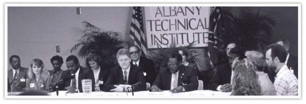Bill Clinton sitting at a table with others at Albany Technical Institute