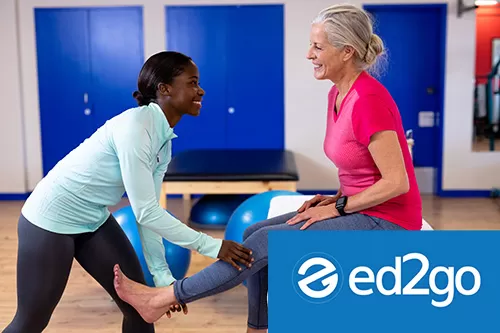 Happy female physiotherapist giving leg massage to active senior woman in sports center.